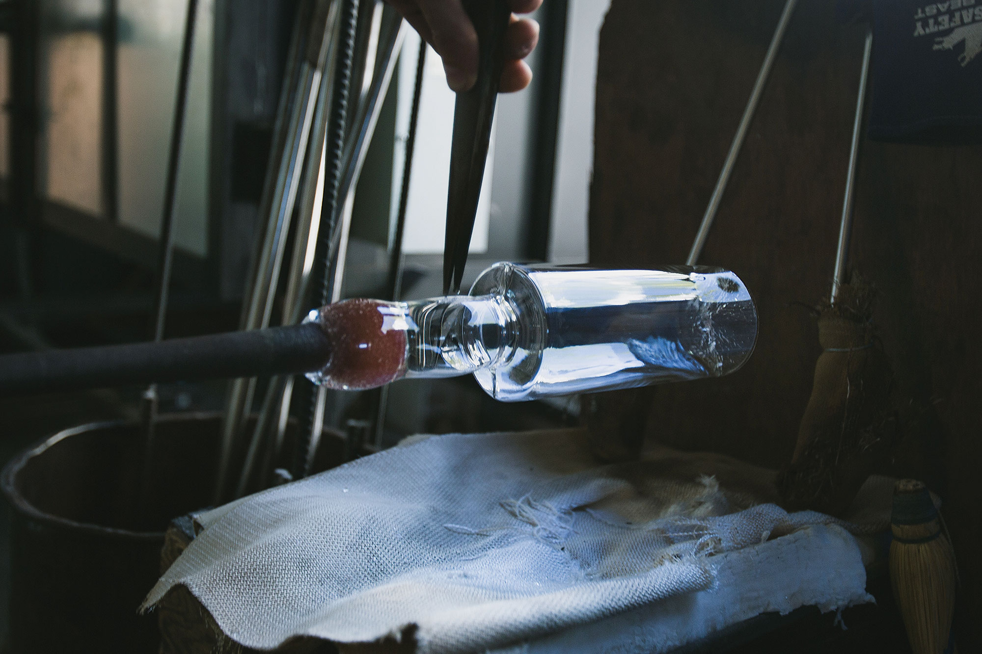 Working clear glass into the shape of a bottle, still on the pipe.