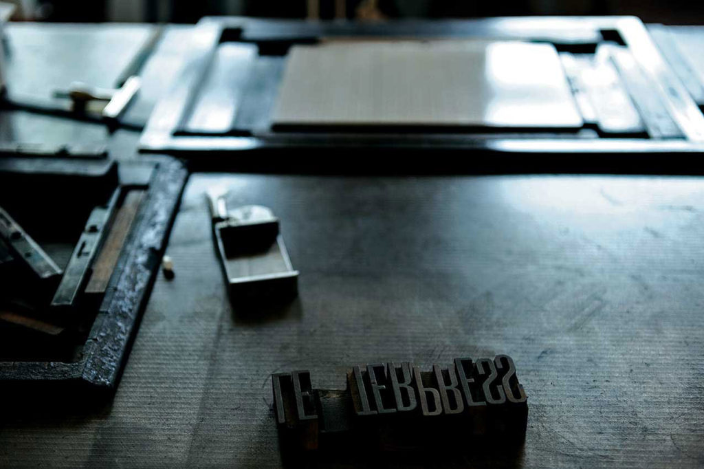 Letters (used for typesetting) set on a table with other printing materials.