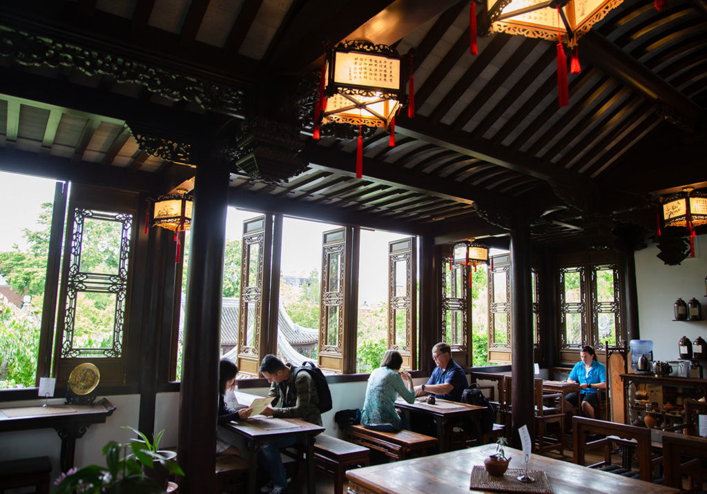 People sitting at tables inside of a Cinese teahouse