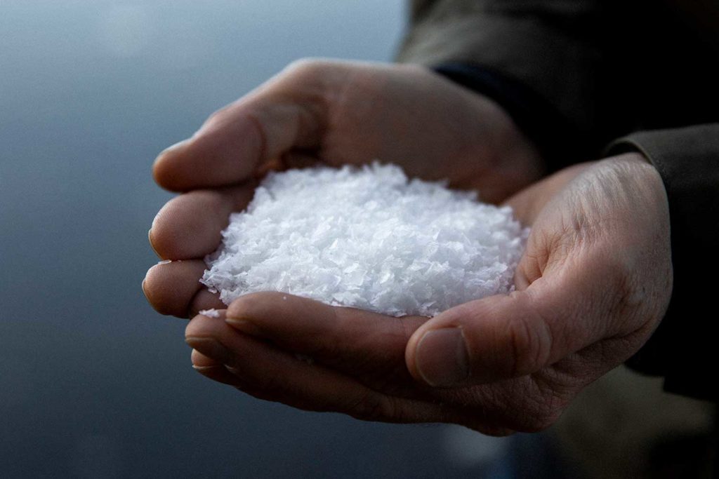 A person holding two hands full of sea salt flakes