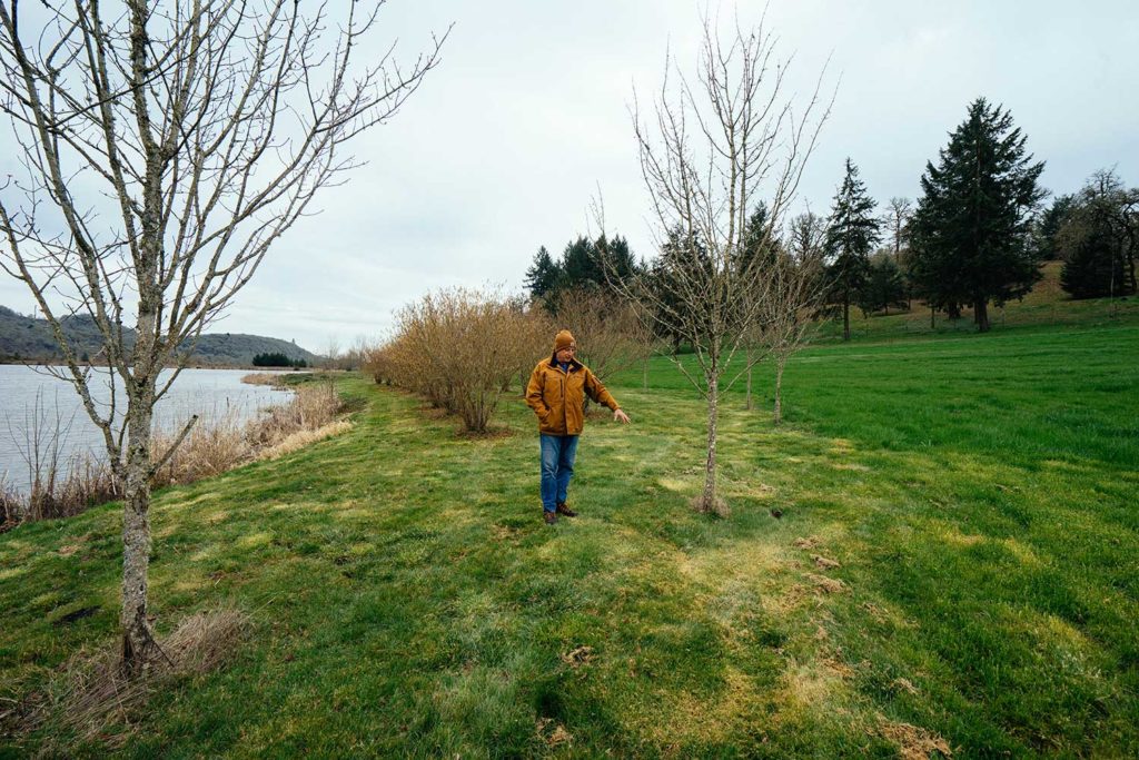A man in an orange coat walking on the banks of a river