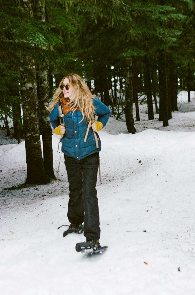 Woman in a blue jacket standing in a snowy forrest