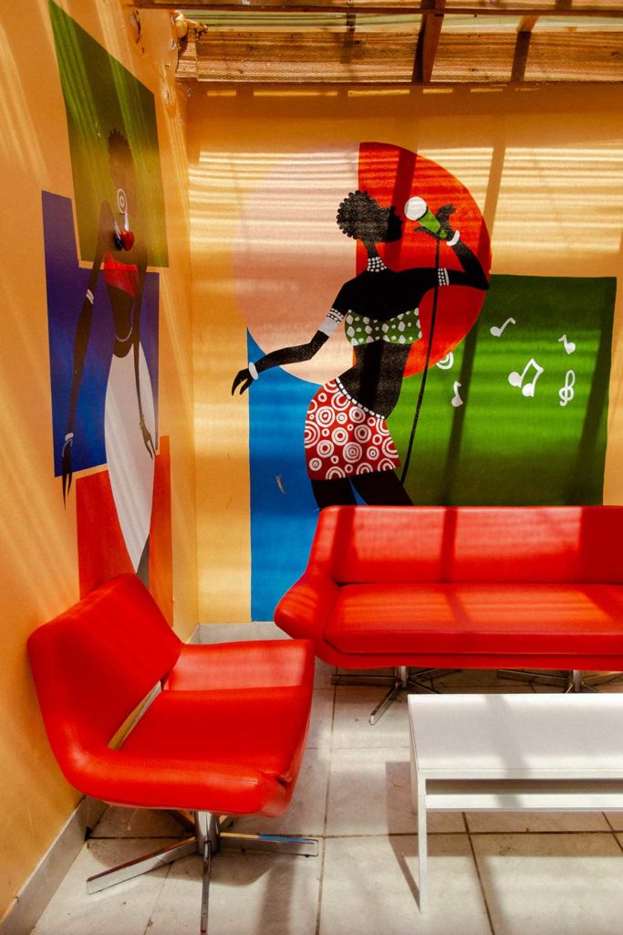 A room with bright red couches and colorful murals on the walls