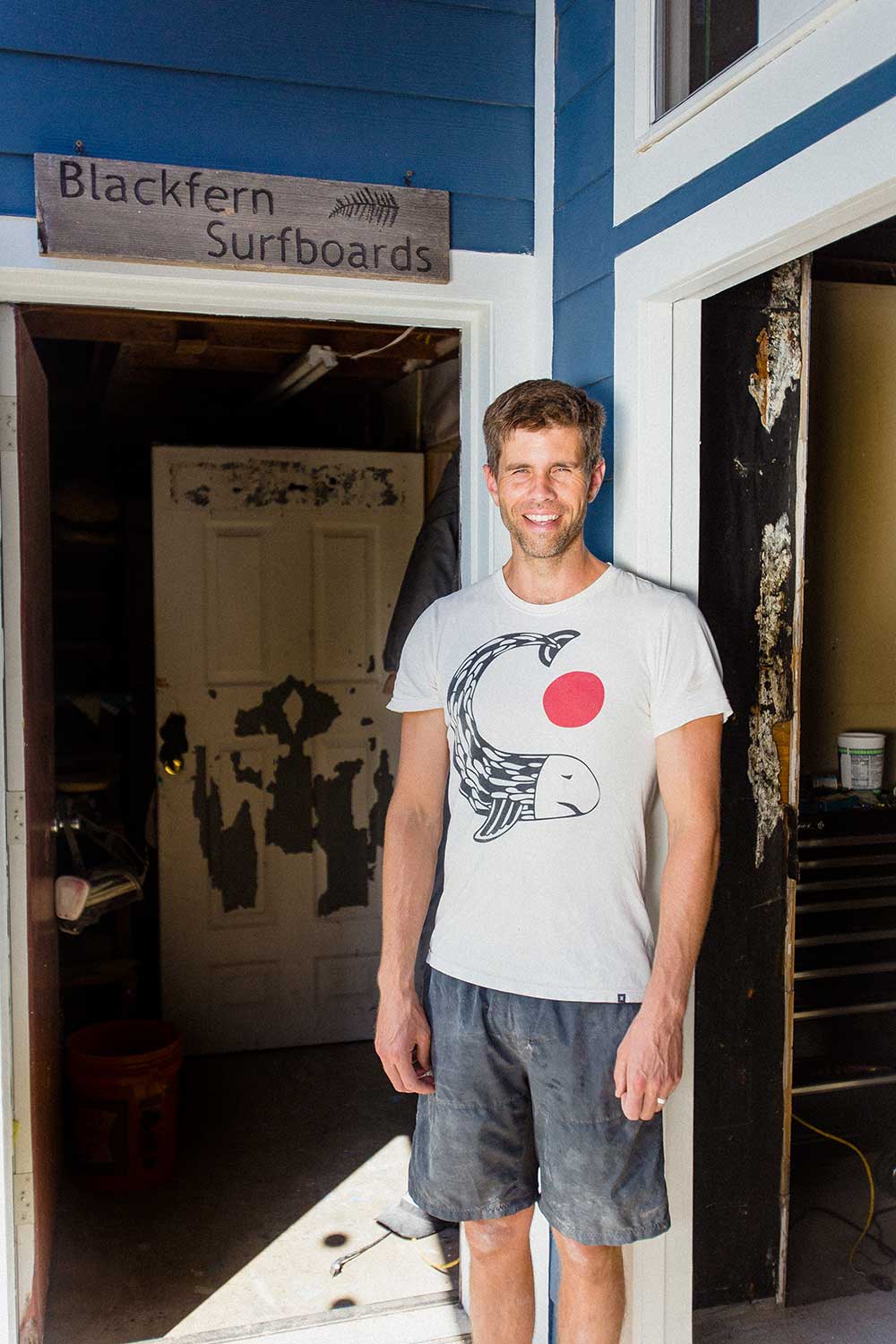 A man standing inside of a surfboard workshop