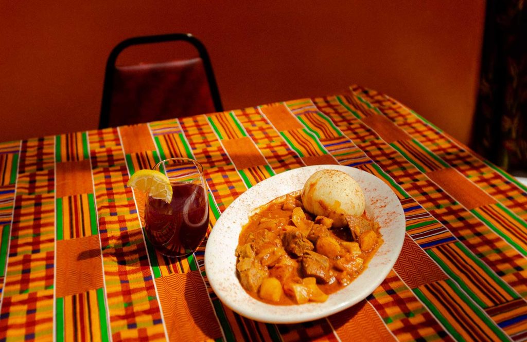 A plate of stew and a drink on a colorful dining room table