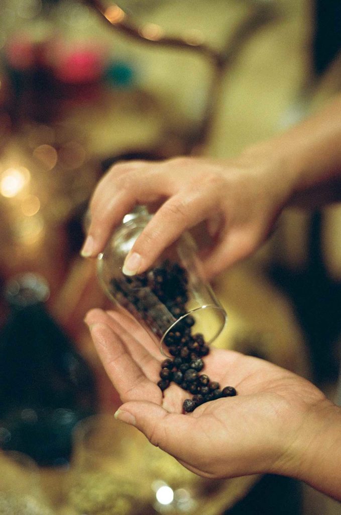 A person pouring dried spices into their hands from a glass cup